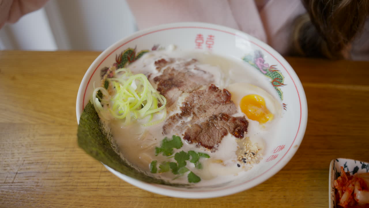 진한 돼지 육수, 차슈, 반숙 달걀, 김, 쪽파가 올려진 김이 모락모락 나는 돈코츠 라멘 클로즈업
