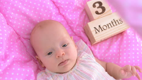 una niña de tres meses en un cojín rosa