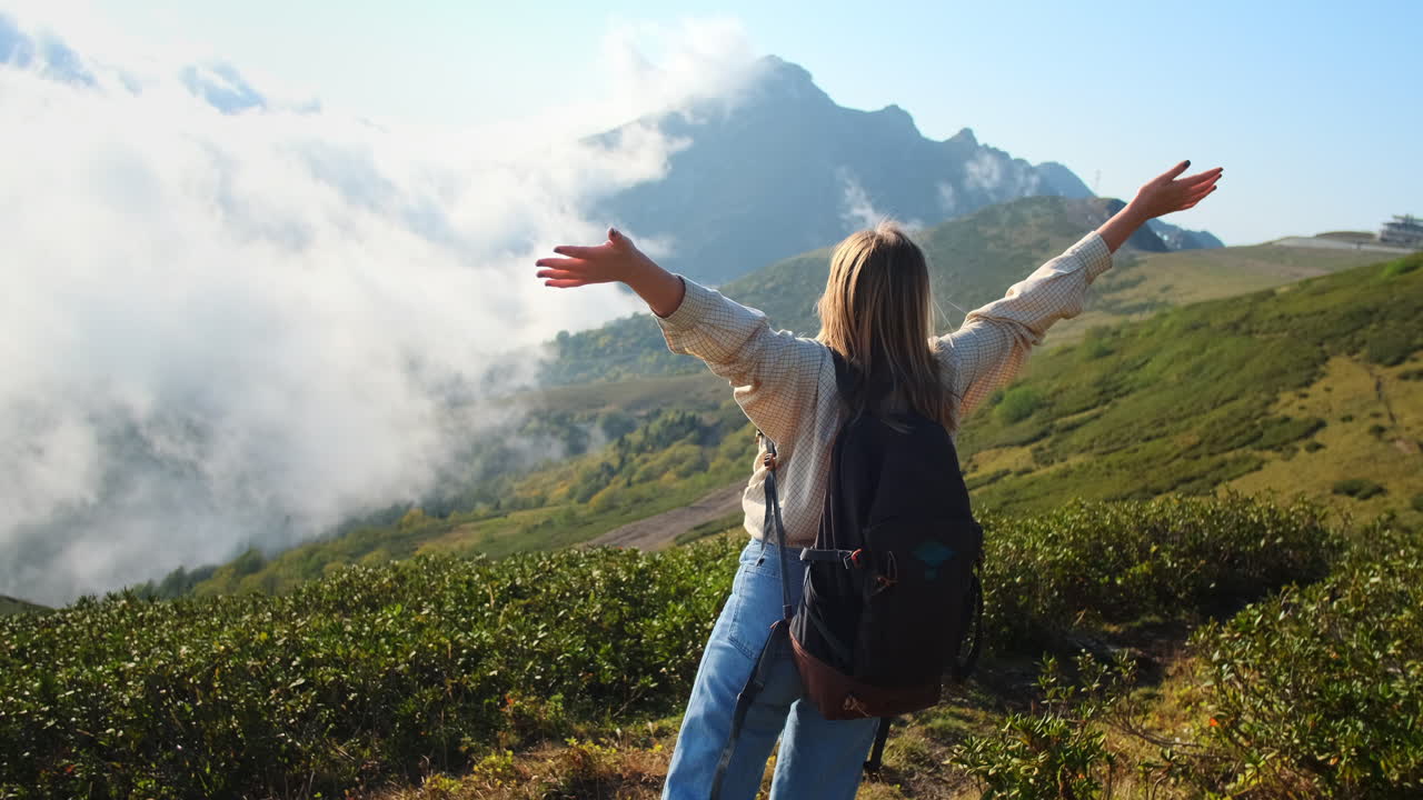 mujer caminando en las montañas con nubes