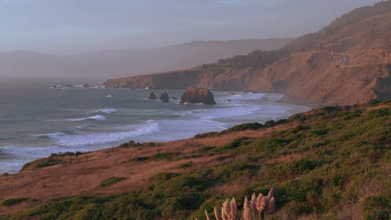 Calm California coast with waves, cliffs, and warm sunset hues