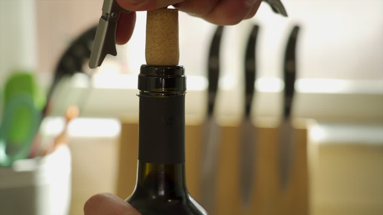 Le mani di un uomo che stappano una bottiglia di vino con un cavatappi