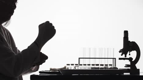 Silhouette-of-a-scientist-in-a-laboratory-puts-on-latex-gloves-before-experimenting---time-lapse-with-white-background-and-copy-space