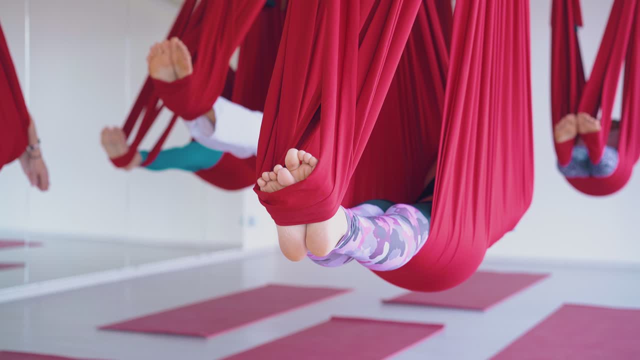 las mujeres se balancean los pies en hamacas de yoga relajándose después del entrenamiento