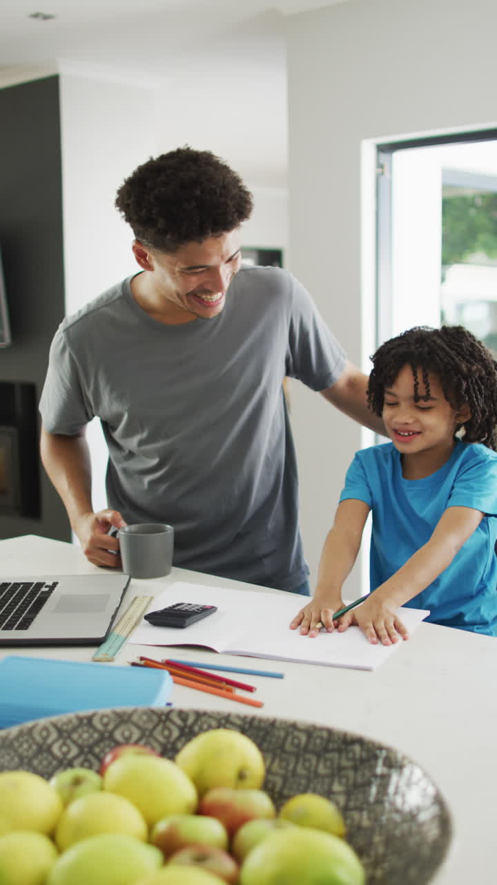 video vertical de un padre biracial feliz con su hijo aprendiendo en casa
