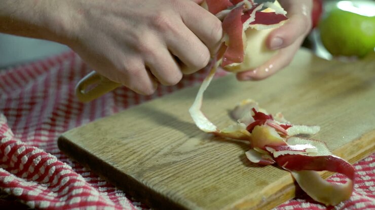 Mela sbucciata. Mani che sbucciano una mela fresca. Cibo sano. Colazione vegana