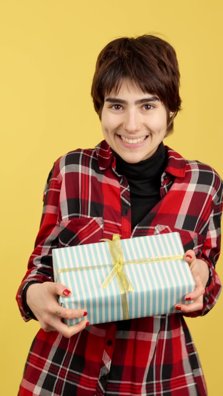 Smiling Woman Holding Gifts on Yellow Background