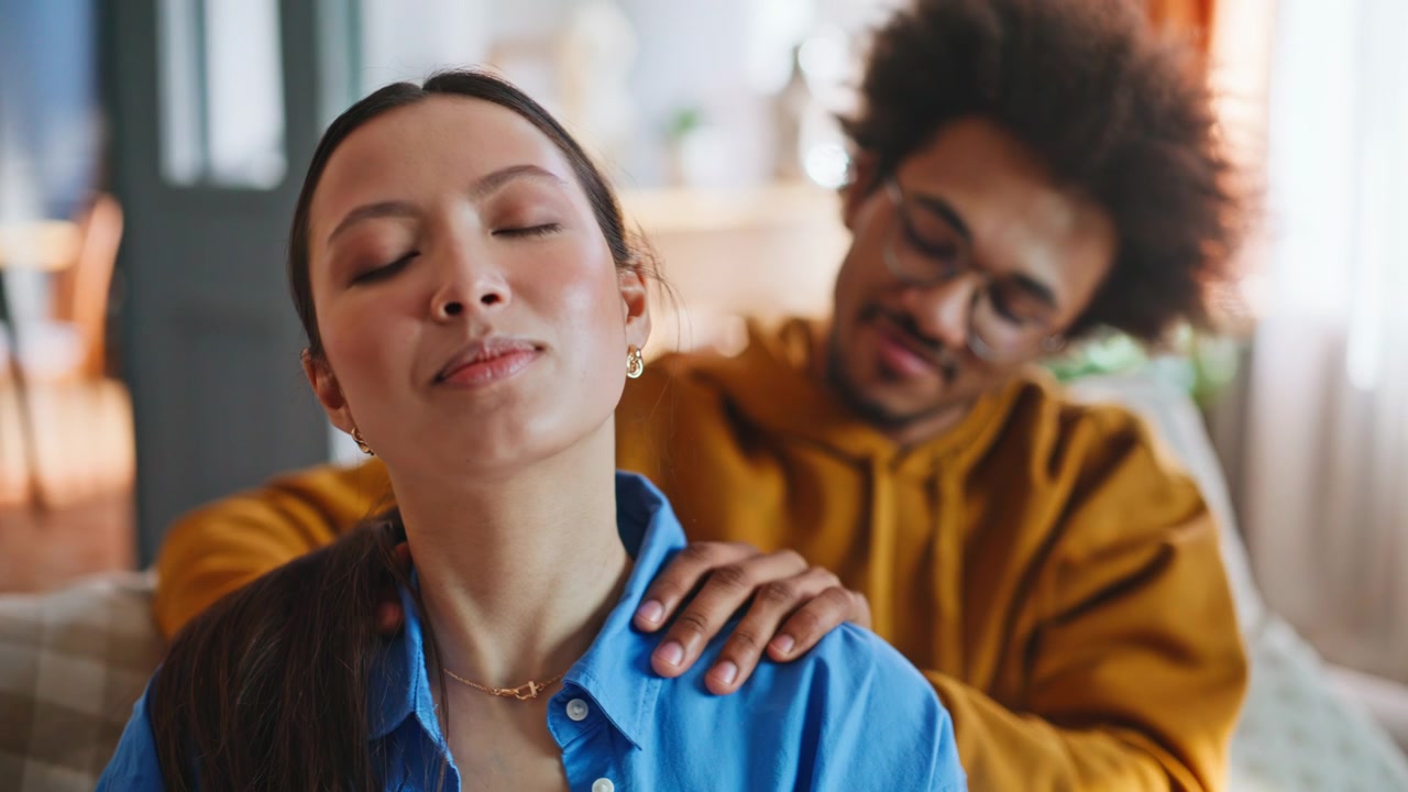 Asian woman receiving shoulder massage from boyfriend home. Relaxing couple