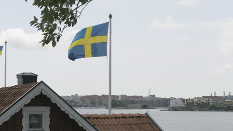 swedish flag by karlskrona seaside with cityscape background, blekinge, sweden