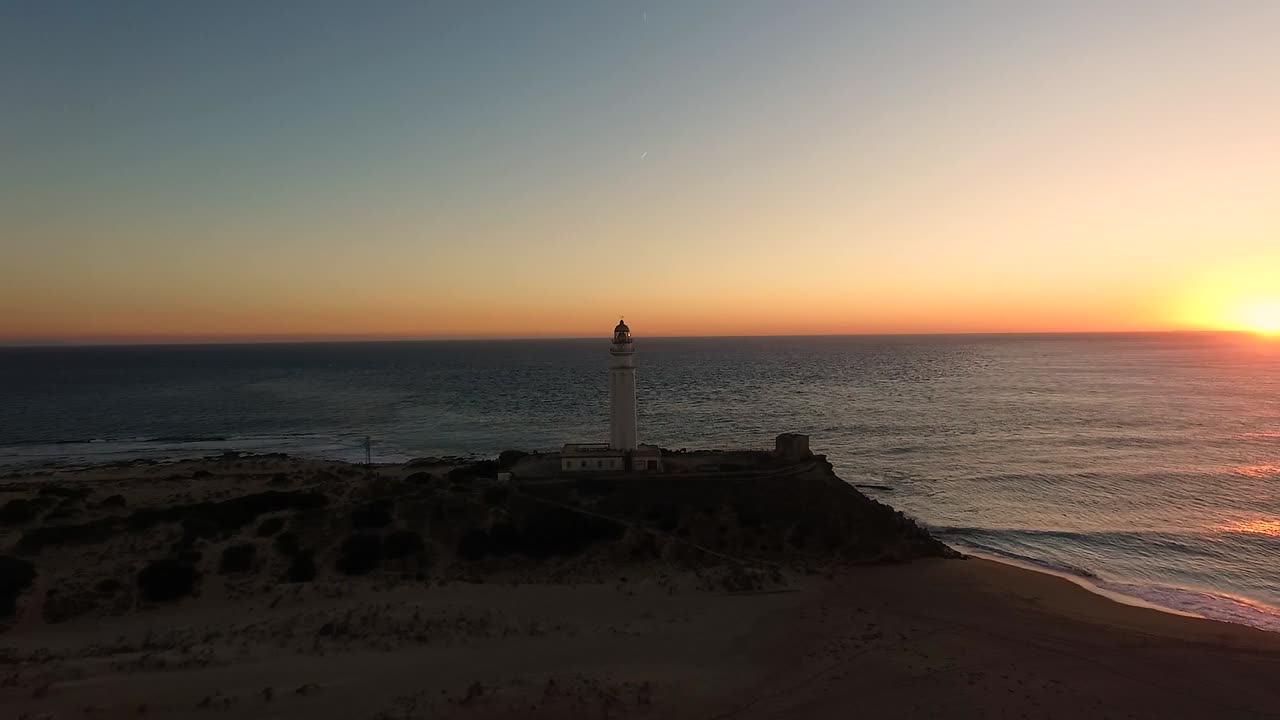 vista de la puesta de sol en el horizonte en el océano vista de drones a última hora de la tarde alrededor del faro de trafalgar en cádiz españa