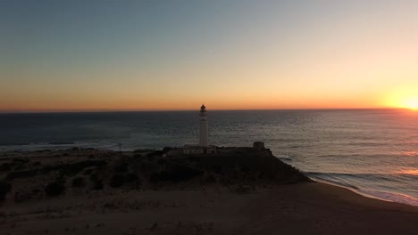 View-of-the-setting-sun-at-horizon-in-the-Ocean-late-evening-drone-view-around-the-Trafalgar-Lighthouse-in-Cadiz-Spain