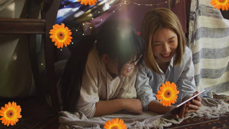animación de flores de naranja sobre madre y hija asiáticas felices usando tableta en casa