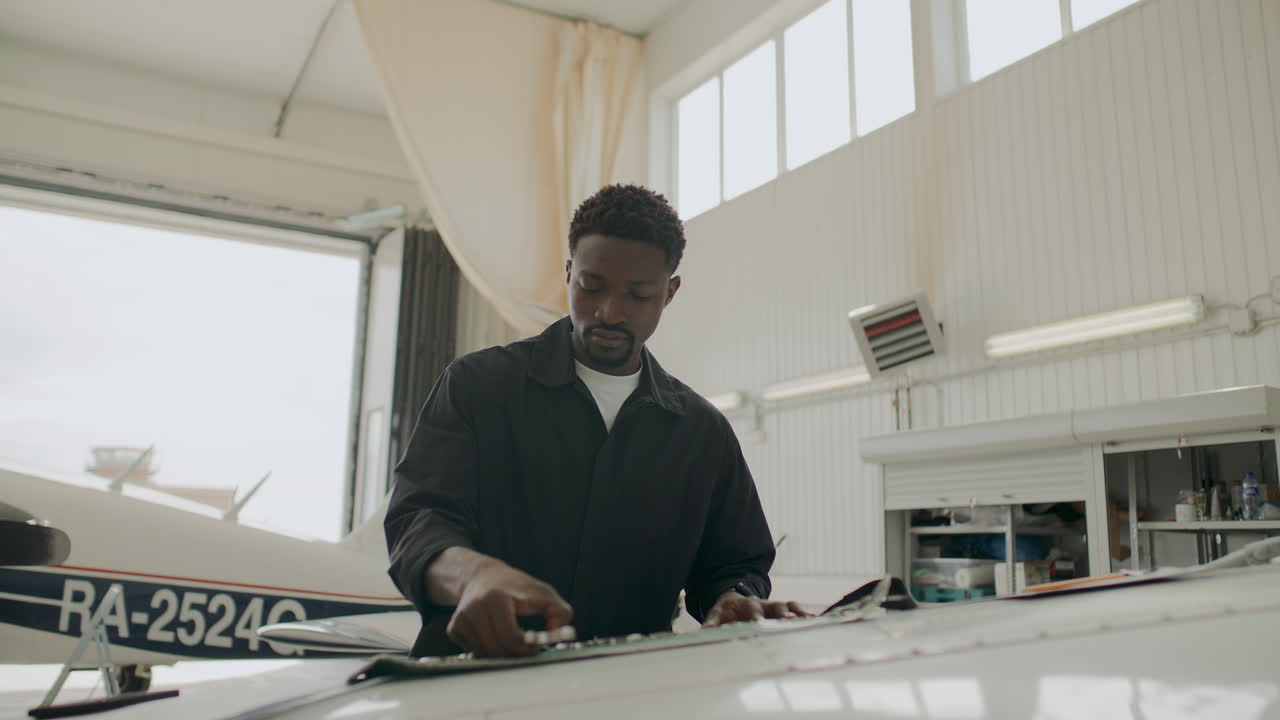 Black Male Technician Taking Wrench to Repair Aircraft in Aviation Hangar