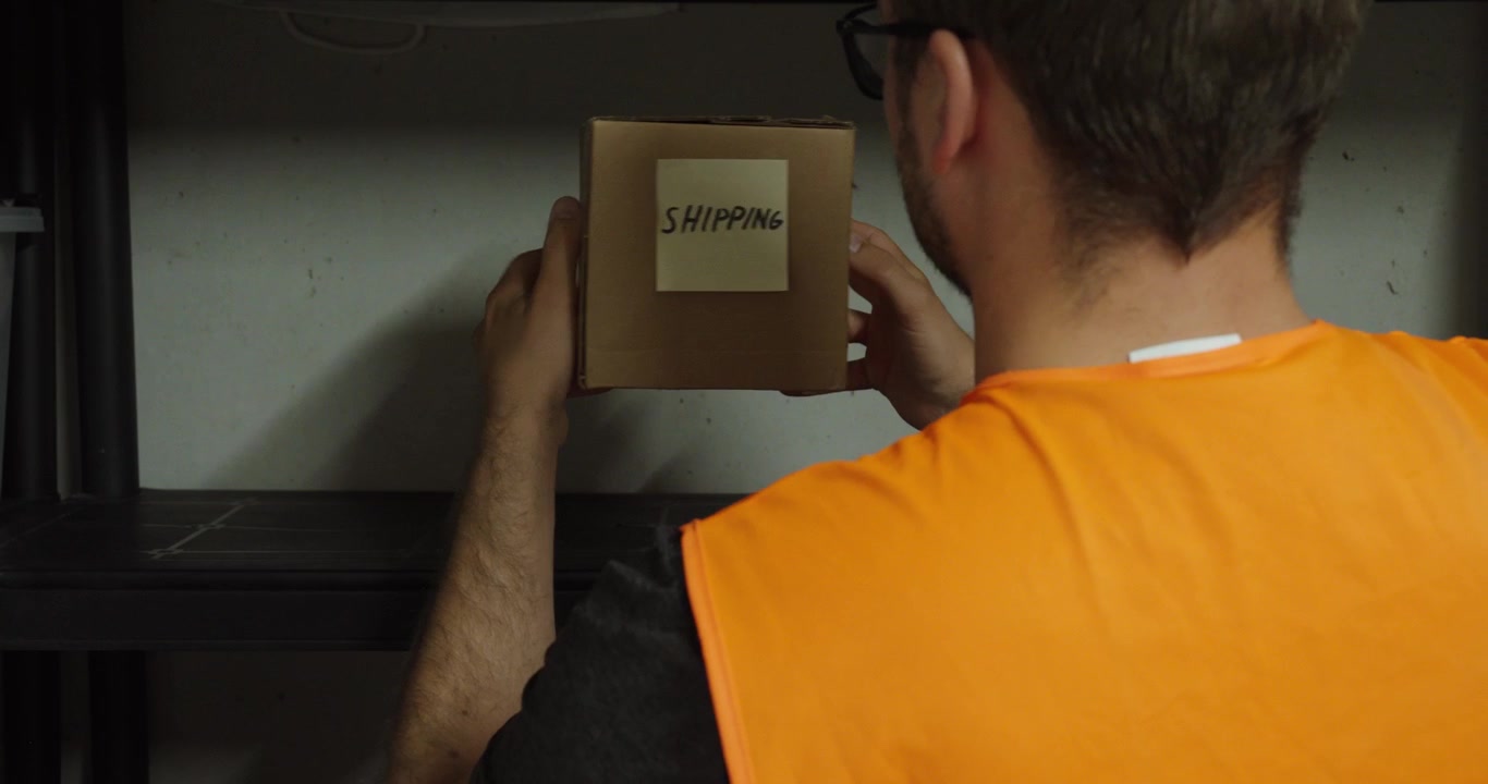 Operaio di magazzino che preleva un pacco per la spedizione da uno scaffale di stoccaggio. Ideale per concetti di logistica, magazzino, e-commerce e gestione degli ordini