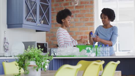 Happy-african-american-mother-and-daughter-recycling-together-in-kitchen