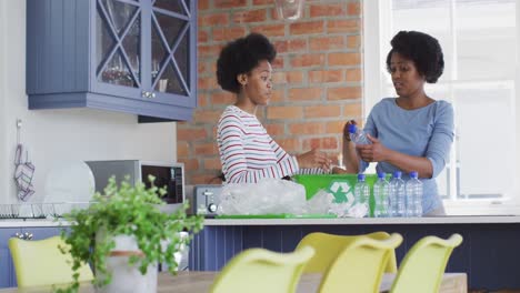 madre y hija afrodescendientes felices reciclando juntos en la cocina