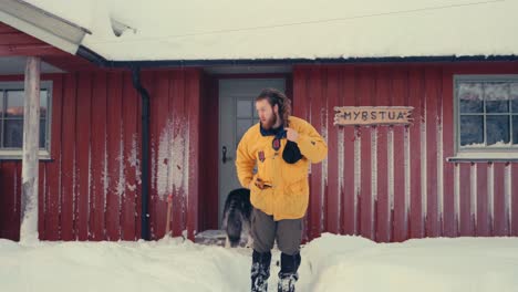 Europäischer-Mann-Vor-Der-Hütte,-Der-Die-Haare-Löst-Und-Im-Winter-Eine-Mütze-Aufsetzt