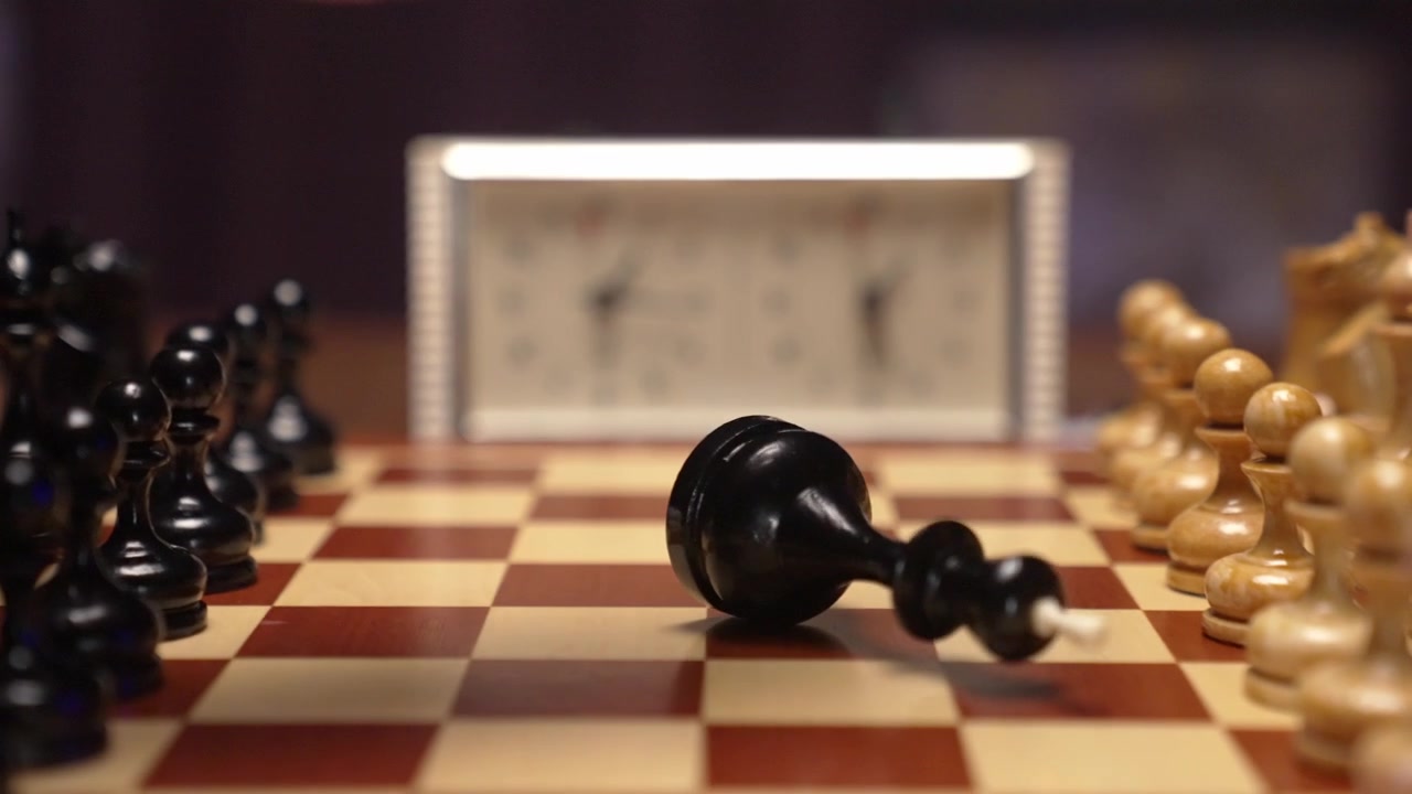 Black Chess King Falls Over on Chessboard in Slow Motion