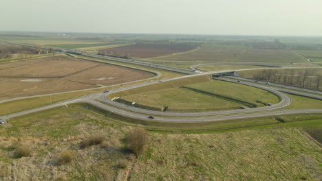 Aerial-drone-flying-around-complex-speed-highway-road-S7-Cdry-intersection-with-ramps-interchanges-and-bridge,-Poland-daytime