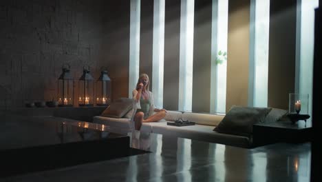 woman sitting in luxury modern spa drinking tea with light rays from windows