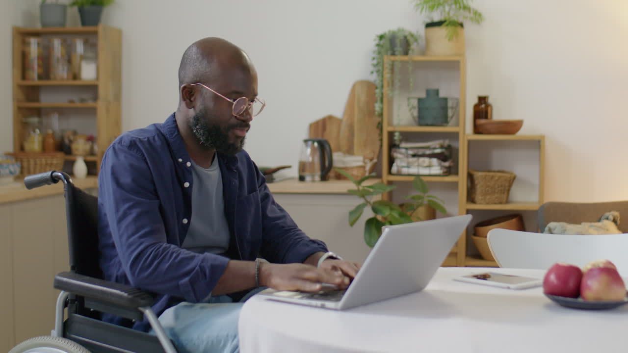 Black Man with Disability Using Laptop and Drinking Juice at Home