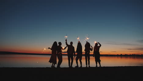 friends celebrating sunset with sparklers on beach