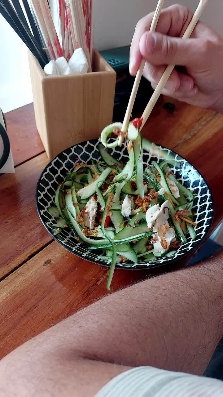 Foodie adding chopped chili to thit ga goi tom or Vietnamese chicken cucumber salad before eating it to add flavor and spice