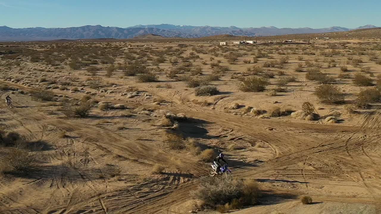 motociclistas disfrutando de una aventura fuera de la carretera en el escarpado desierto de mojave con salto alto - vista aérea en cámara lenta