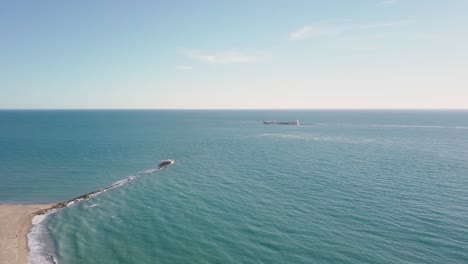 Panorama-Des-Blauen-Meeres-Mit-Sancti-Petri-Wellenbrecher-Und-Burg-In-Der-Ferne-In-Chiclana-De-La-Frontera,-Spanien