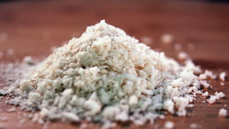 Close-Interior-Shot-of-bread-Crumbs-In-a-Pile-on-a-Wooden-Surface-with-More-Falling-On-Top-From-the-Top