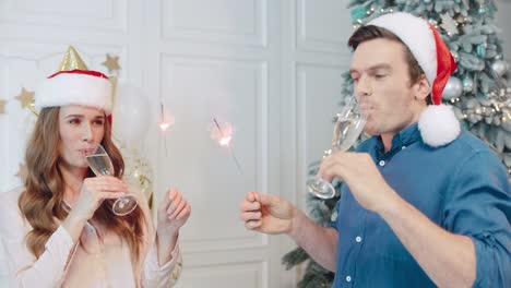 hombre y mujer alegres haciendo codeaciones y abrazos con gorros de papá noel.