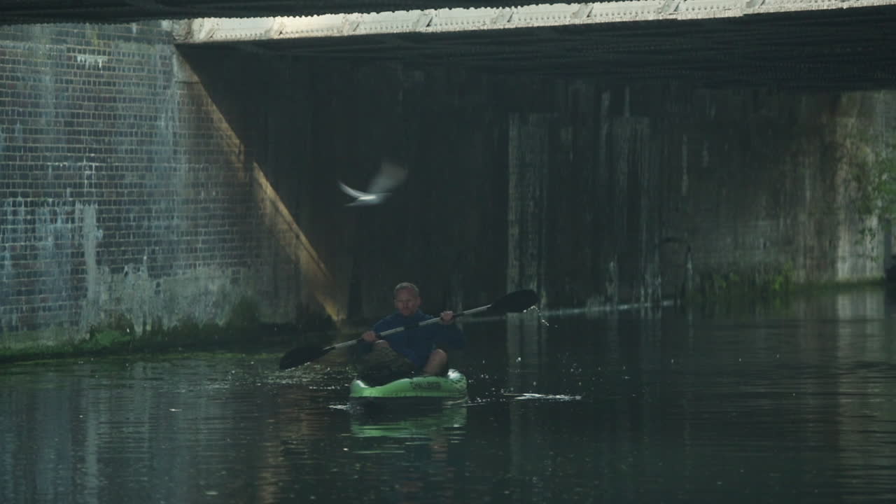 A man on a kayaking adventure in a urban setting