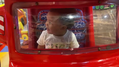 almost 2 year old baby riding a electric toy car in a mall