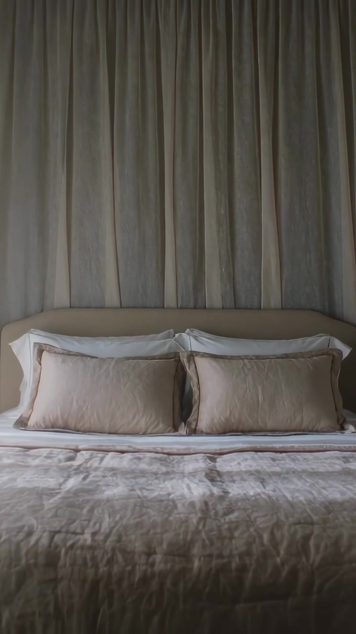 Video verticale: Una brezza scosta una tenda trasparente in camera da letto, rivelando un letto allestito e la testiera.