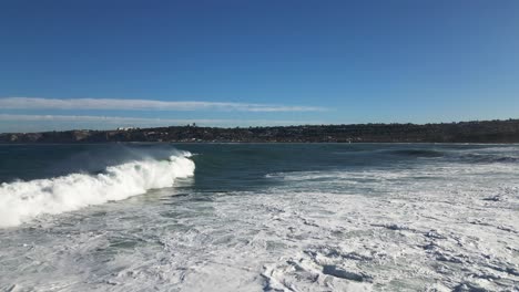 4K-Zeitlupenaufnahmen-Von-Großen-Meereswellen,-Die-Bei-Flut-In-Der-Bucht-Von-La-Jolla-In-San-Diego,-Kalifornien,-Auf-Klippen-Krachen,-Während-Ein-Pelikan-Vorbeifliegt