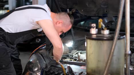 mechanic working on car engine in a workshop