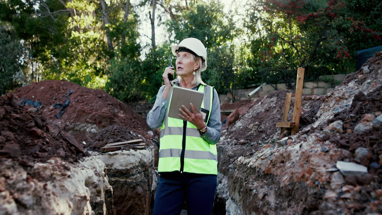 Woman worker with walkie-talkie and tablet on construction site