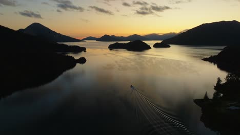 Vista-Aérea-Del-Amanecer-Dorado-Con-Un-Barco-Que-Viaja-A-Través-De-Aguas-Tranquilas-Y-Plácidas-En-El-Sonido-Pelorus-Te-Hoiere-En-Los-Sonidos-De-Marlborough,-Isla-Sur-De-Nueva-Zelanda-Aotearoa