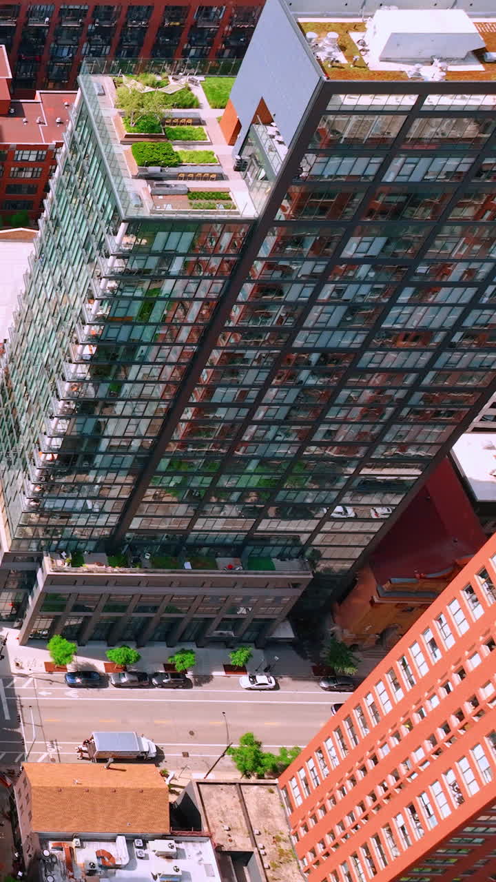 Top view of the roof and facades of multi-story buildings and the street with cars. Aerial view of downtown Chicago. Vertical video