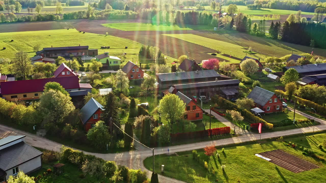 Colorful Rural Village in Latvia Surrounded by Fields and Forest at Sunset in Drone Video