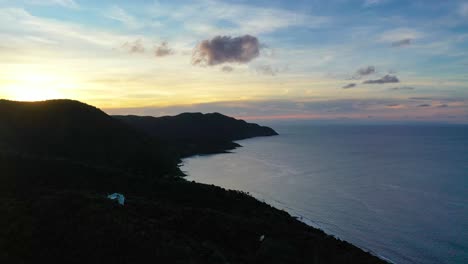 aerial drone captures the calm caribbean sea near st. croix, with a radiant sky full of soft pinks and purples glowing above a lush peninsula and peaceful shoreline in the early morning