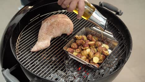 chef drizzling olive oil over potatoes on a hot grill with pork beef