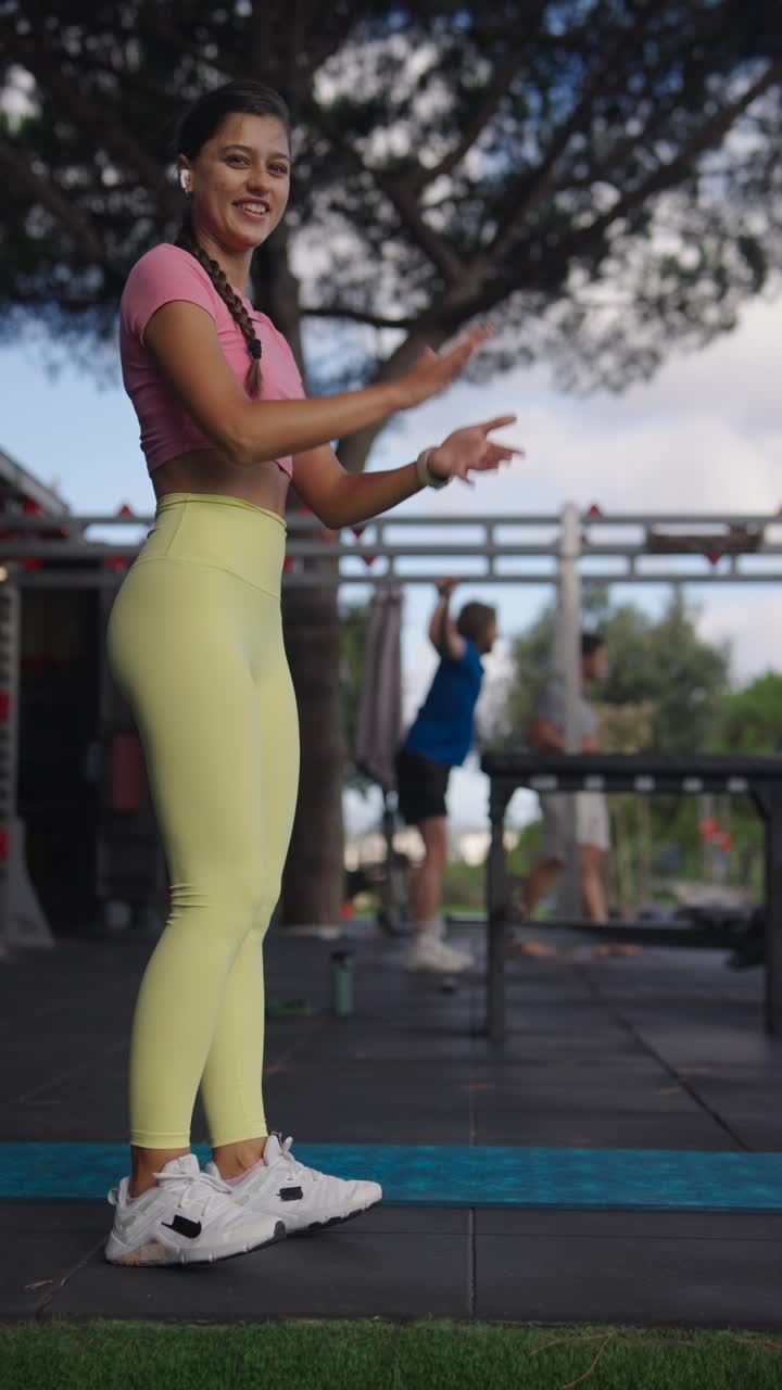 A woman pets a bulldog at an outdoor gym while exercising