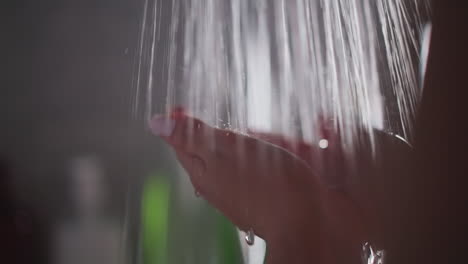 woman cupping hands under flowing stream. woman takes pleasure in warmth of hot water. young lady stands under comforting spray of hot water