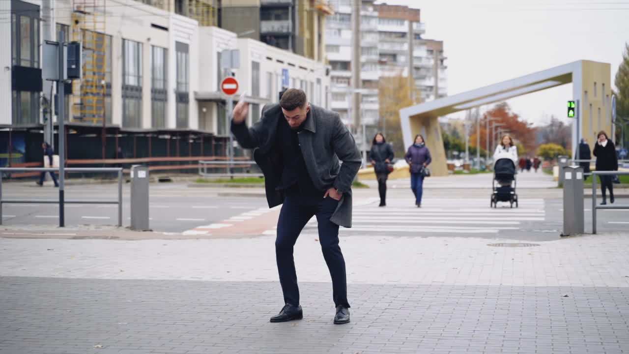 Nervous businessman talking on phone in the city. Annoyed man using mobile phone and breaking it on asphalt in the street city. Slow motion.