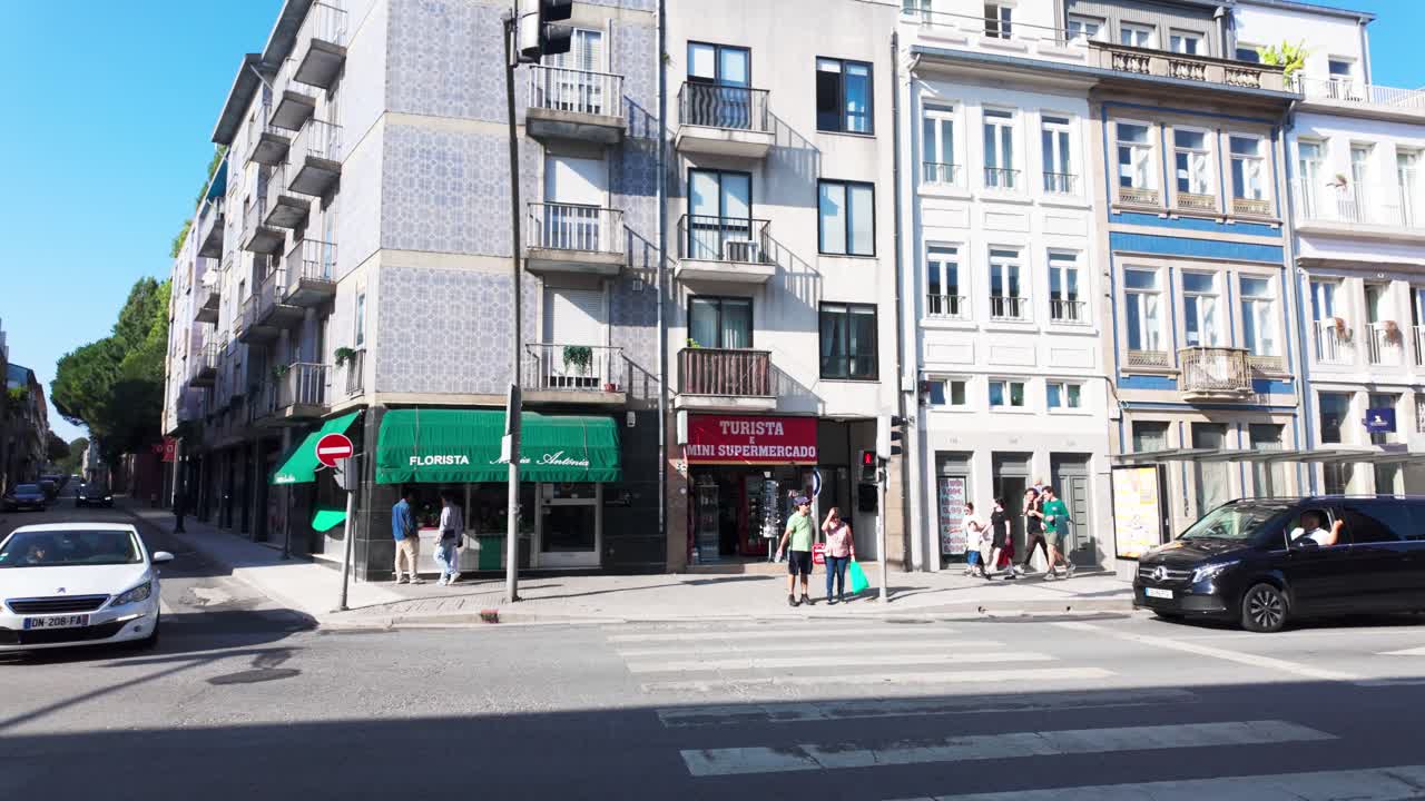A red tourist bus drives down a sunny street in Porto near historic buildings