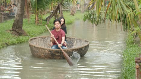 young asian couple are rowing a circle boat in a canal.