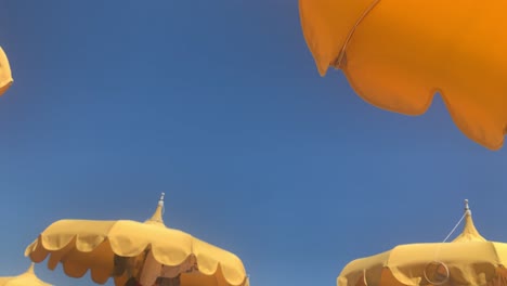 low angle perspective of yellow beach umbrellas on blue sky background