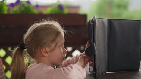 calm little child touches screen of tablet at rustic table