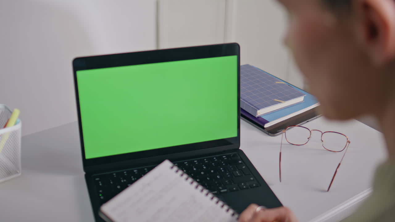 Tutor checking notes mockup laptop workplace closeup. Woman looking green screen