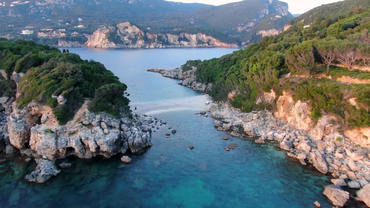Stunning aerial drone flight over the iconic twin beach of Limni Glyko in Paleokastritsa, Corfu, revealing turquoise Ionian Sea and lush cliffs